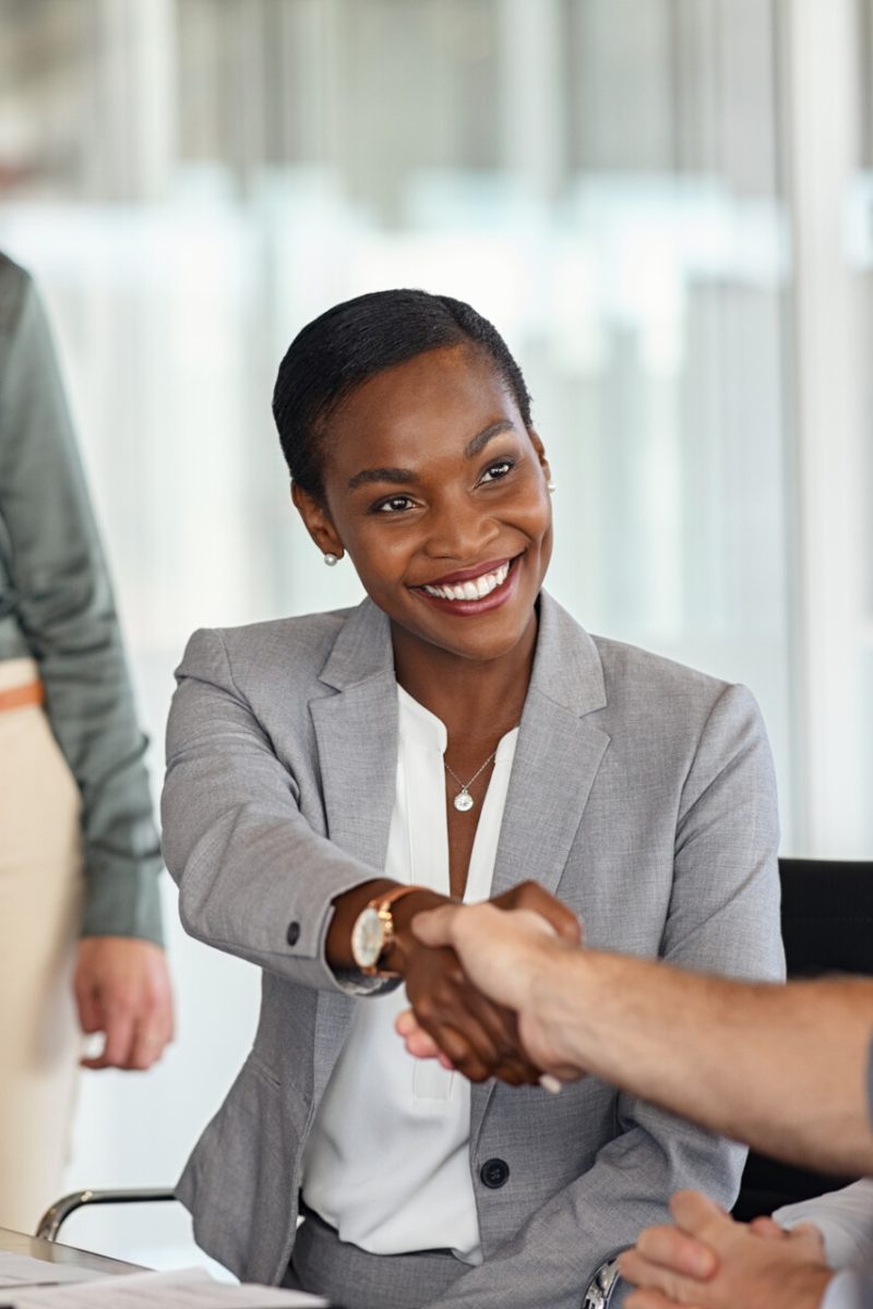 Happy black businesswoman and businessman shaking hands at meeting. Professional business executive leaders making handshake agreement. Happy business man closing deal at negotiations with african american woman.